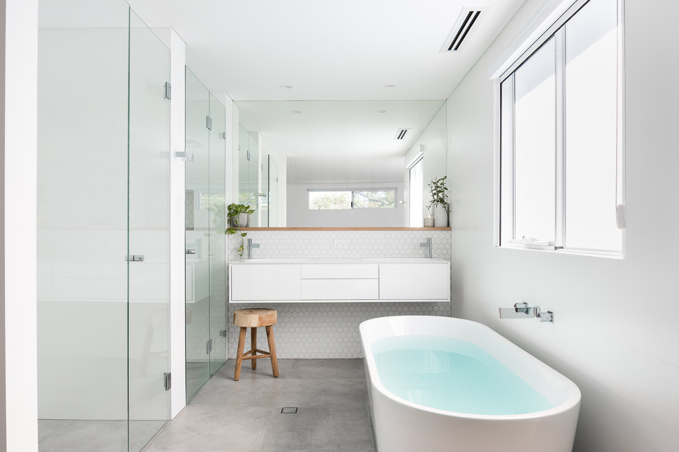Inspiration for a mid-sized contemporary master bathroom in Perth with white cabinets, a freestanding tub, white tile, ceramic tile, white walls, porcelain floors, an integrated sink, grey floor, white benchtops, a curbless shower, a hinged shower door and flat-panel cabinets.