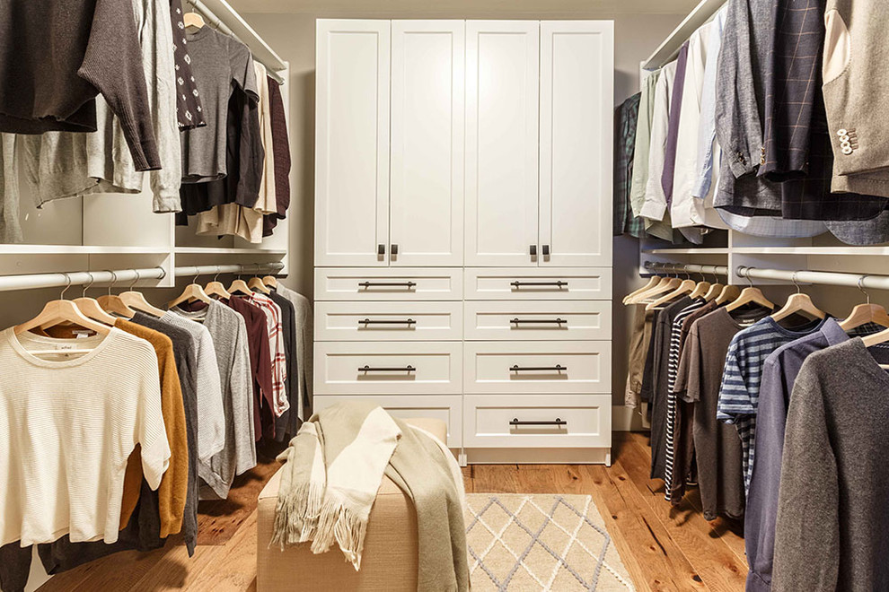 Inspiration for a mid-sized transitional walk-in wardrobe in Edmonton with recessed-panel cabinets, white cabinets, light hardwood floors and brown floor.