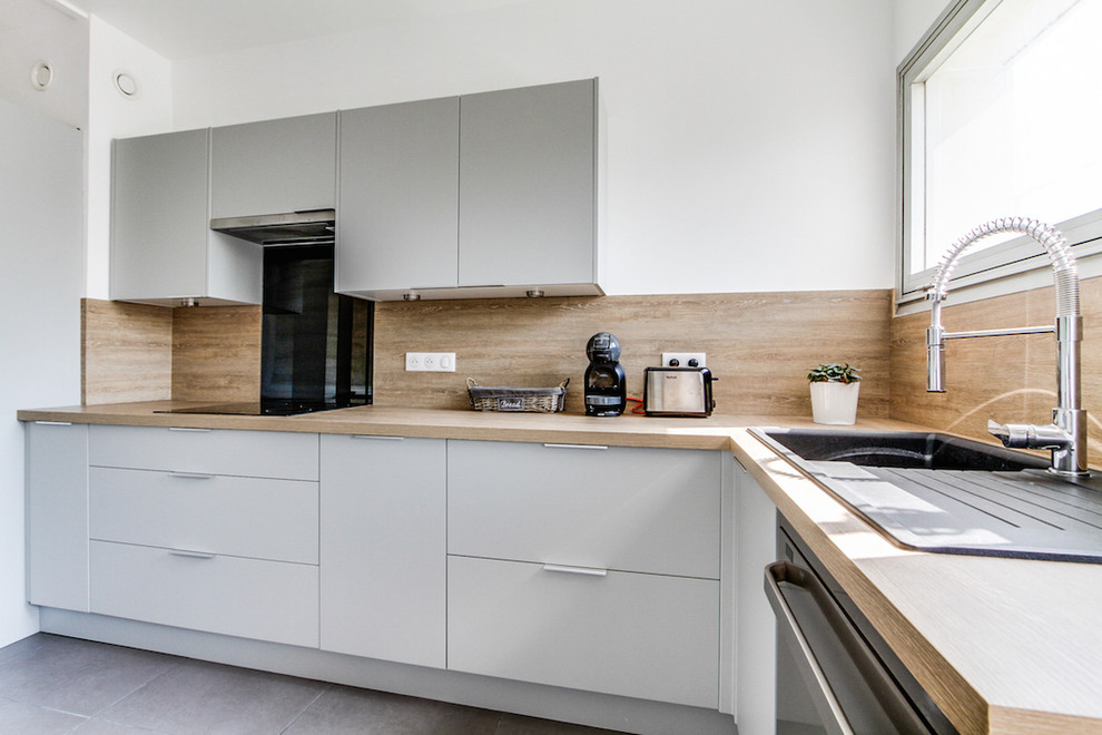 Large scandinavian l-shaped separate kitchen in Paris with a single-bowl sink, beaded inset cabinets, grey cabinets, laminate benchtops, beige splashback, black appliances, ceramic floors, no island, grey floor and beige benchtop.