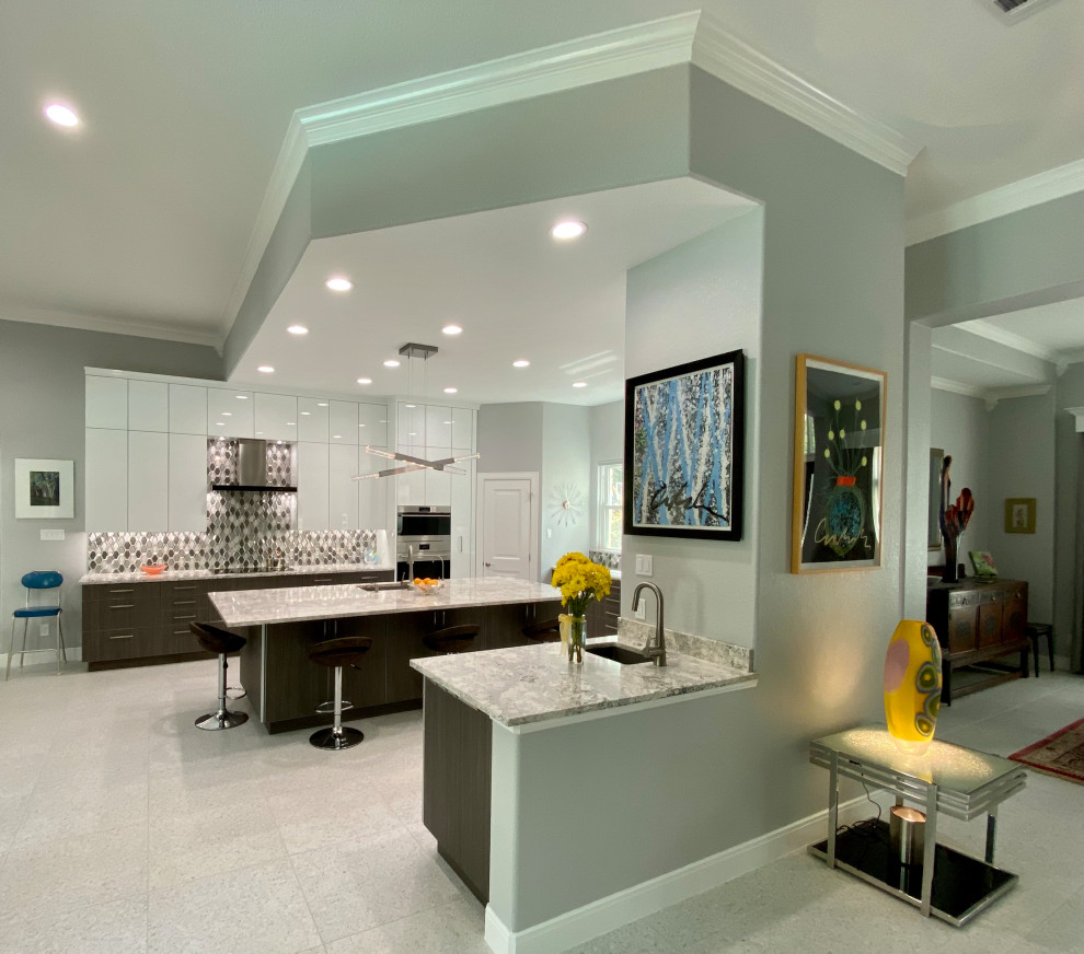 Inspiration for an expansive contemporary u-shaped open plan kitchen in Houston with a submerged sink, flat-panel cabinets, white cabinets, engineered stone countertops, multi-coloured splashback, glass tiled splashback, integrated appliances, terrazzo flooring, an island, white floors, grey worktops and feature lighting.