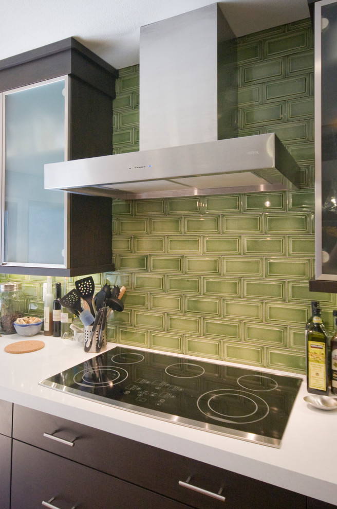 Eat-in kitchen - mid-sized transitional l-shaped medium tone wood floor eat-in kitchen idea in San Francisco with flat-panel cabinets, dark wood cabinets, quartz countertops, green backsplash, subway tile backsplash, black appliances and an island
