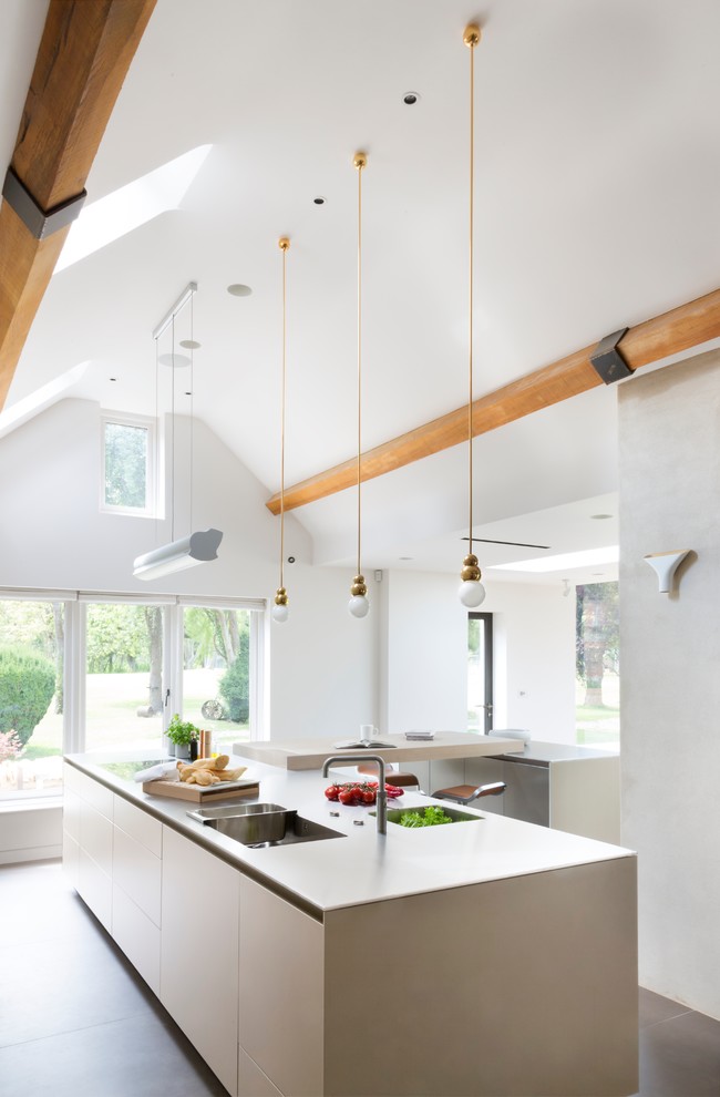 This is an example of a contemporary kitchen in Oxfordshire with flat-panel cabinets, light wood cabinets, concrete floors and multiple islands.