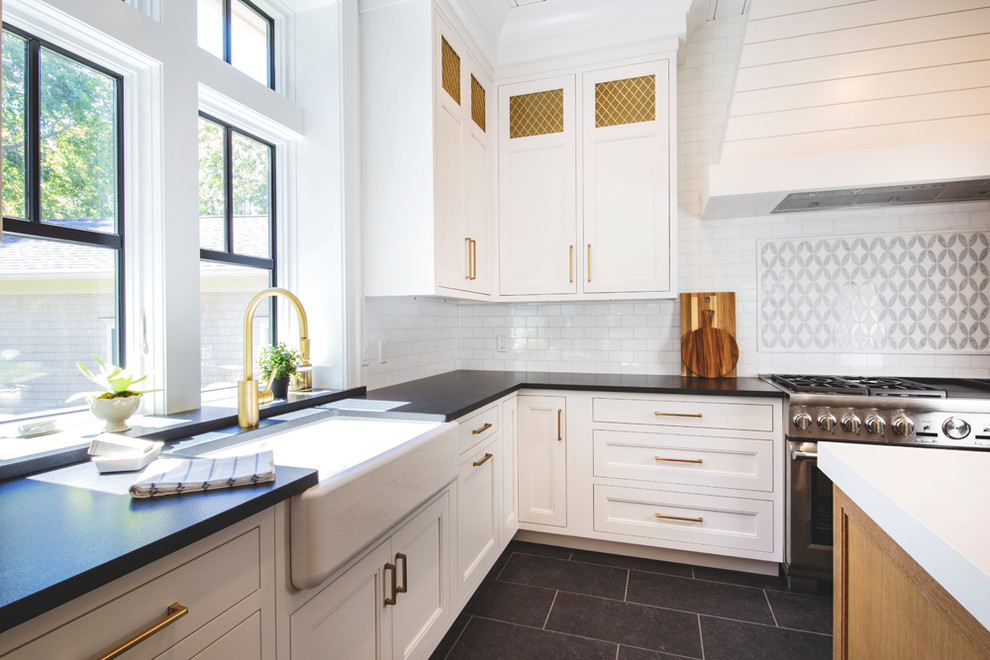Contemporary eat-in kitchen in New York with white cabinets, white splashback, marble splashback, stainless steel appliances, with island and black benchtop.
