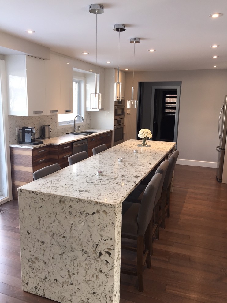 This is an example of a contemporary galley eat-in kitchen in Montreal with flat-panel cabinets, white cabinets, stainless steel appliances, medium hardwood floors, with island, an undermount sink, terrazzo benchtops, white splashback and stone slab splashback.