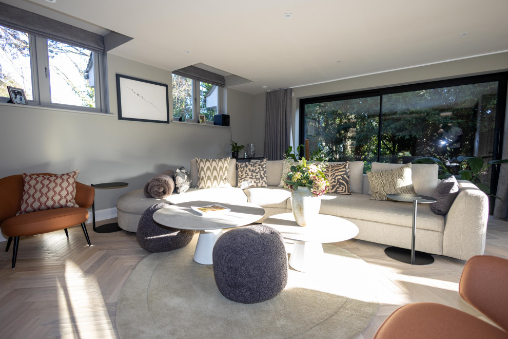 Стильный дизайн: гостиная комната в стиле модернизм с серыми стенами, светлым паркетным полом и мультимедийным центром - последний тренд