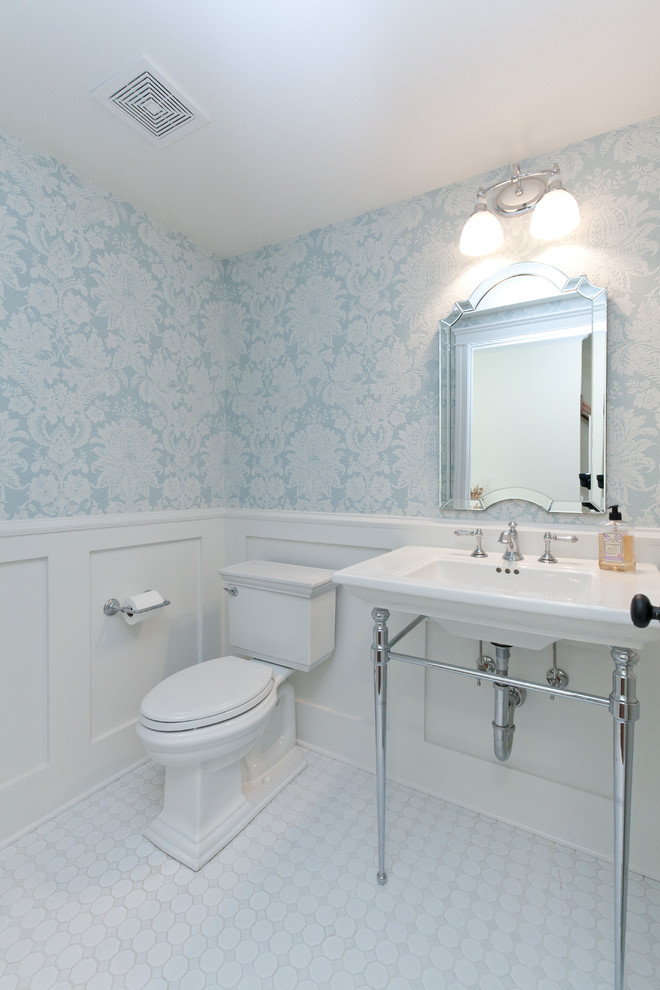 Photo of a mid-sized country powder room in Chicago with a two-piece toilet, ceramic floors, a pedestal sink, white floor, open cabinets, blue walls, solid surface benchtops, white benchtops, a freestanding vanity and wallpaper.