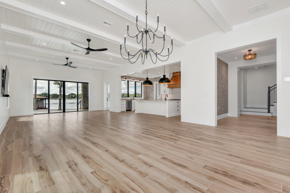 Mid-sized country open concept family room in Orlando with white walls, porcelain floors, a freestanding tv, beige floor, timber and planked wall panelling.