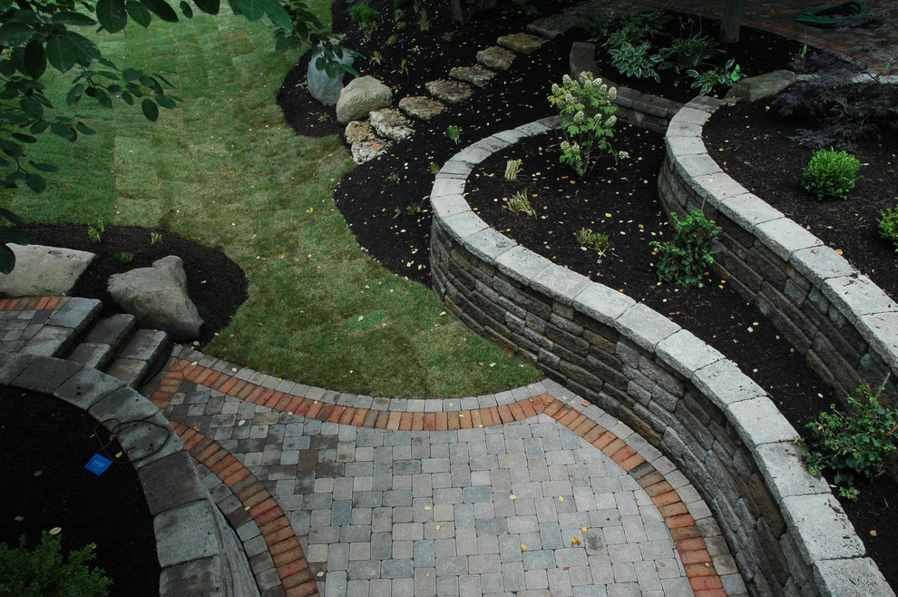 Inspiration for an expansive eclectic backyard shaded garden in Columbus with a retaining wall and natural stone pavers.
