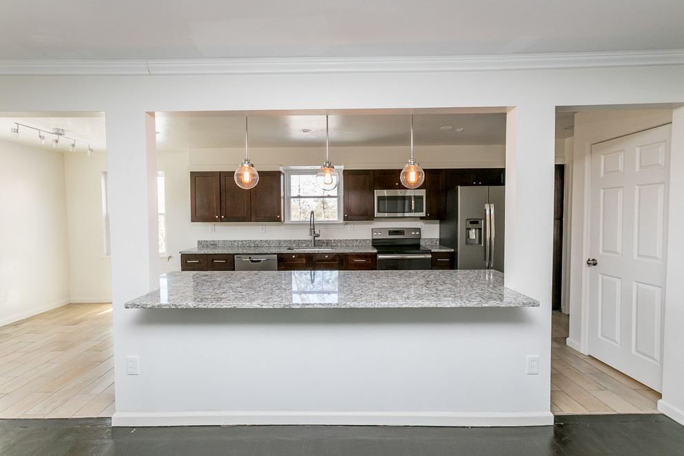 Example of a mid-sized transitional galley beige floor and porcelain tile open concept kitchen design in DC Metro with an undermount sink, shaker cabinets, dark wood cabinets, granite countertops, gray backsplash, stainless steel appliances, an island and gray countertops