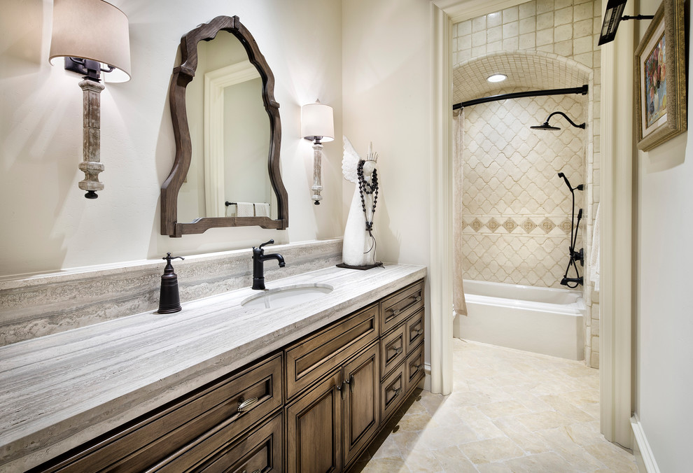 Design ideas for an expansive traditional bathroom in Austin with raised-panel cabinets, medium wood cabinets, an undermount tub, beige tile, an undermount sink, a shower/bathtub combo, beige walls, a shower curtain and beige benchtops.