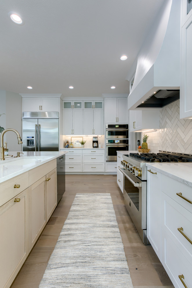 Inspiration for a transitional light wood floor and beige floor open concept kitchen remodel with an undermount sink, white cabinets, quartzite countertops, multicolored backsplash, stainless steel appliances and an island