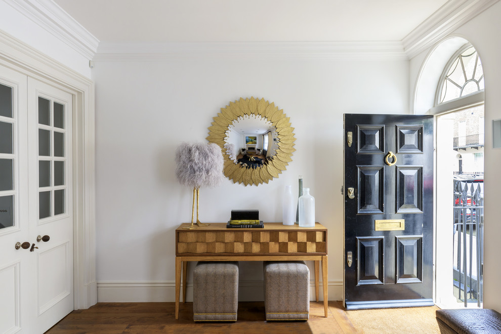 Design ideas for a mid-sized transitional entryway in London with white walls, dark hardwood floors, a black front door and brown floor.