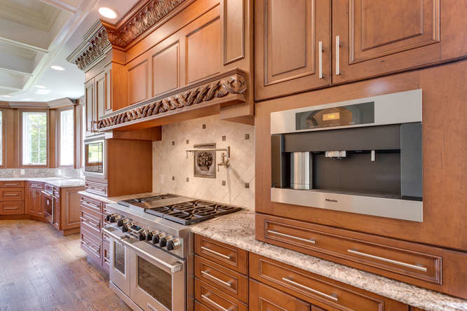 This is an example of a large traditional single-wall open plan kitchen in DC Metro with a double-bowl sink, medium wood cabinets, beige splashback, stainless steel appliances, medium hardwood floors, beaded inset cabinets, granite benchtops, metal splashback and multiple islands.