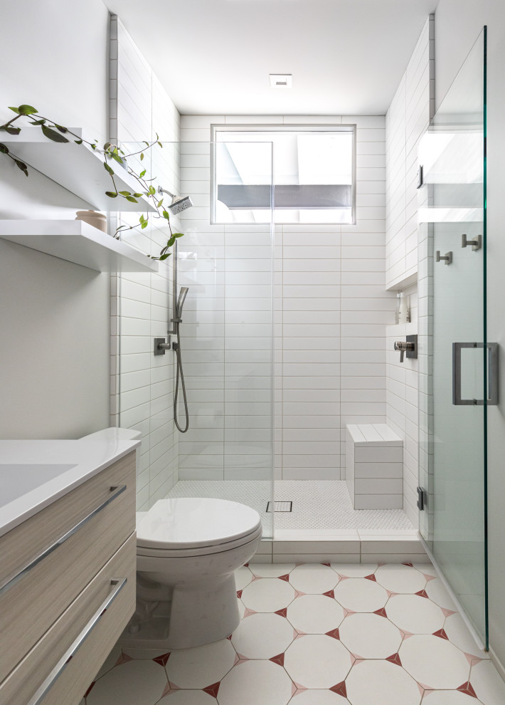 サクラメントにあるミッドセンチュリースタイルのおしゃれなバスルーム (浴槽なし) (フラットパネル扉のキャビネット、アルコーブ型シャワー、白いタイル、一体型シンク、マルチカラーの床、開き戸のシャワー、白い洗面カウンター、ニッチ、シャワーベンチ、洗面台1つ、フローティング洗面台) の写真
