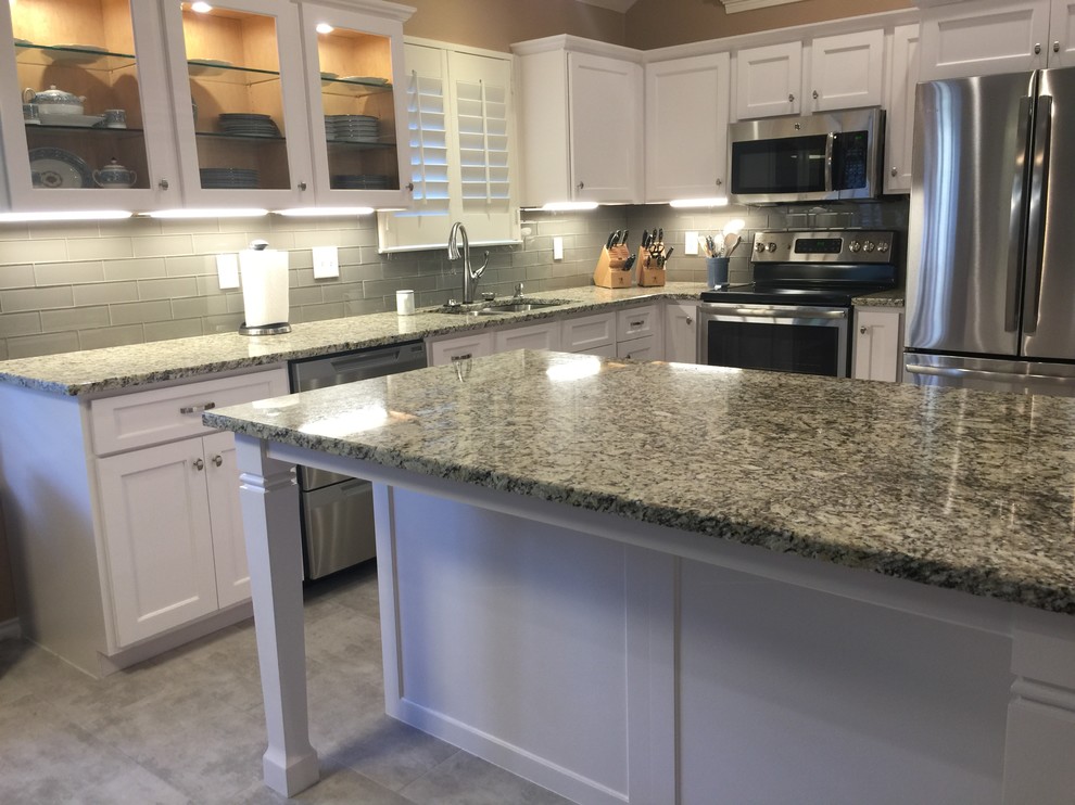 Example of a mid-sized transitional l-shaped porcelain tile eat-in kitchen design in Austin with an undermount sink, shaker cabinets, white cabinets, granite countertops, white backsplash, glass tile backsplash, stainless steel appliances and an island