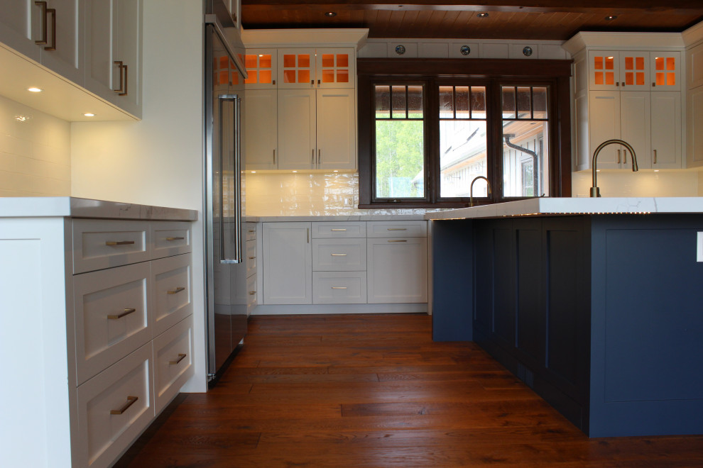 Large mountain style u-shaped dark wood floor, brown floor and wood ceiling eat-in kitchen photo in Toronto with a farmhouse sink, shaker cabinets, white cabinets, quartz countertops, white backsplash, subway tile backsplash, stainless steel appliances, an island and white countertops