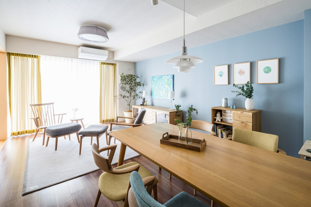 Cette photo montre une salle à manger ouverte sur le salon scandinave de taille moyenne avec un mur bleu et un sol en bois brun.