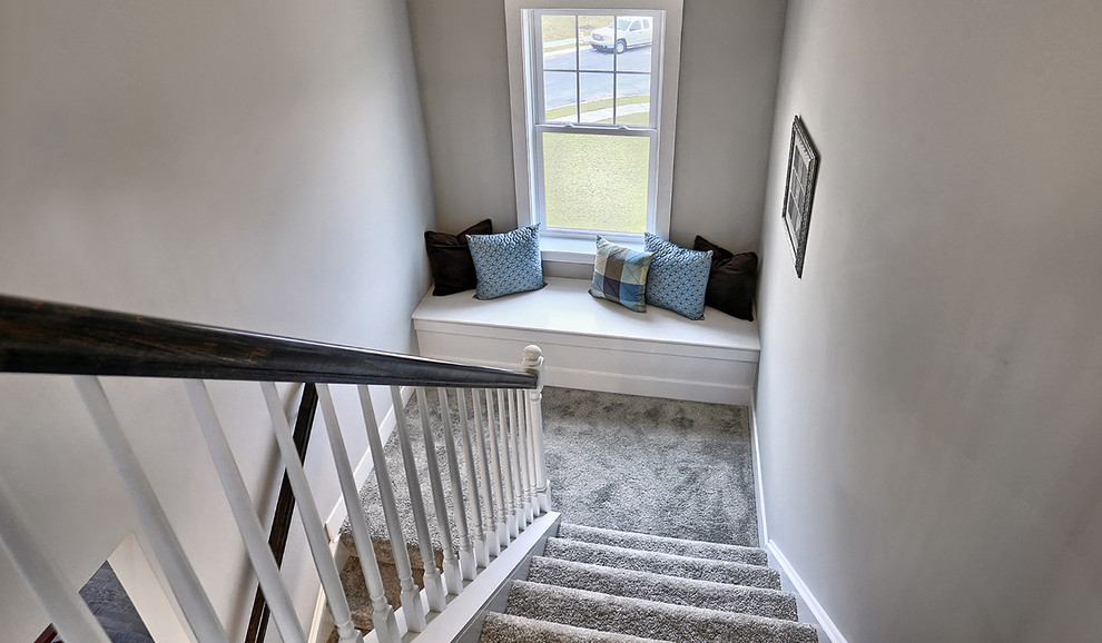 Photo of a large transitional carpeted u-shaped staircase in Other with carpet risers and wood railing.