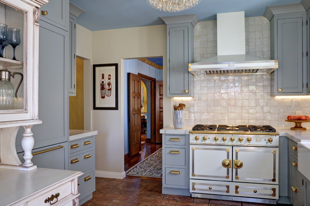 This is an example of a mid-sized transitional u-shaped kitchen pantry in San Francisco with a farmhouse sink, beaded inset cabinets, blue cabinets, quartz benchtops, beige splashback, terra-cotta splashback, stainless steel appliances, porcelain floors, brown floor and beige benchtop.