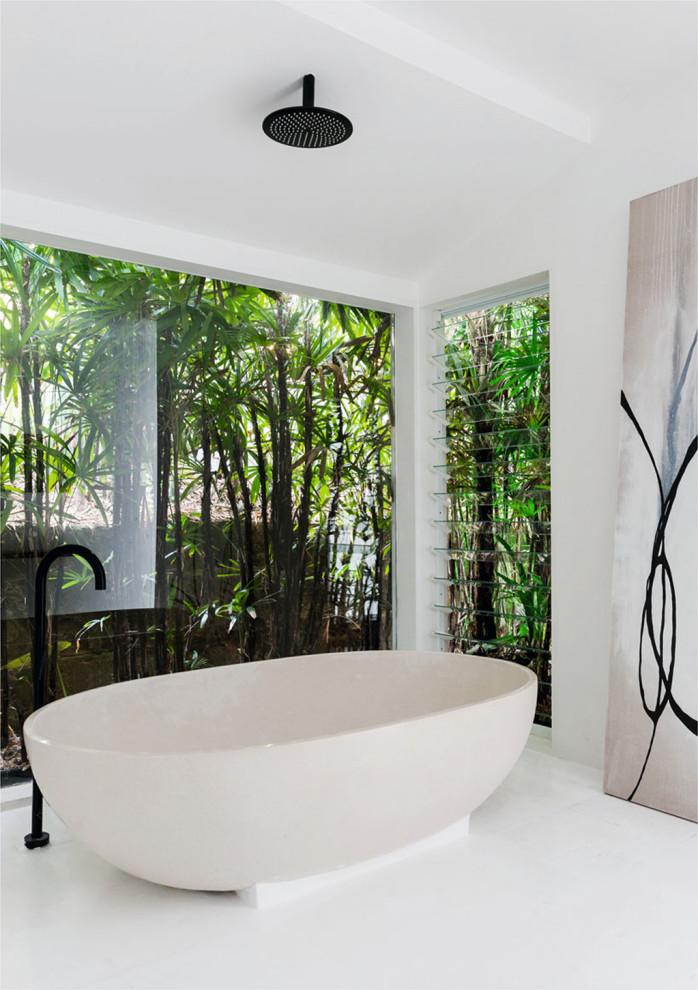 Large tropical master bathroom in Sydney with a freestanding tub, white walls and white floor.