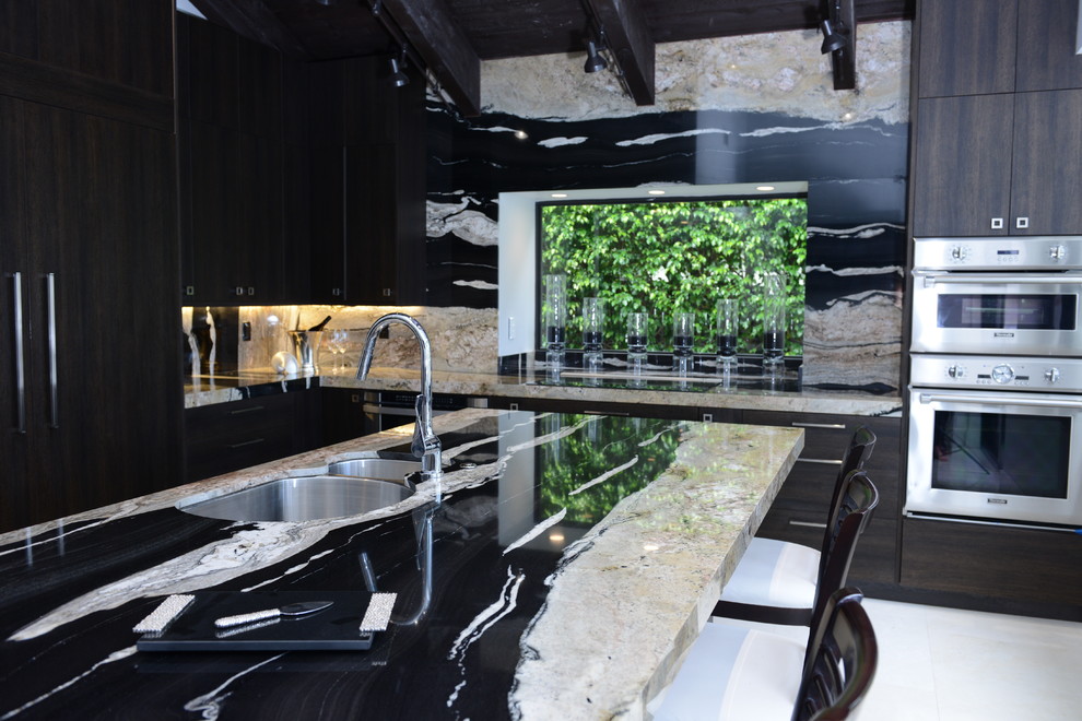 Inspiration for a large contemporary l-shaped open plan kitchen in Miami with an undermount sink, flat-panel cabinets, dark wood cabinets, granite benchtops, black splashback, stone slab splashback, stainless steel appliances, marble floors and with island.