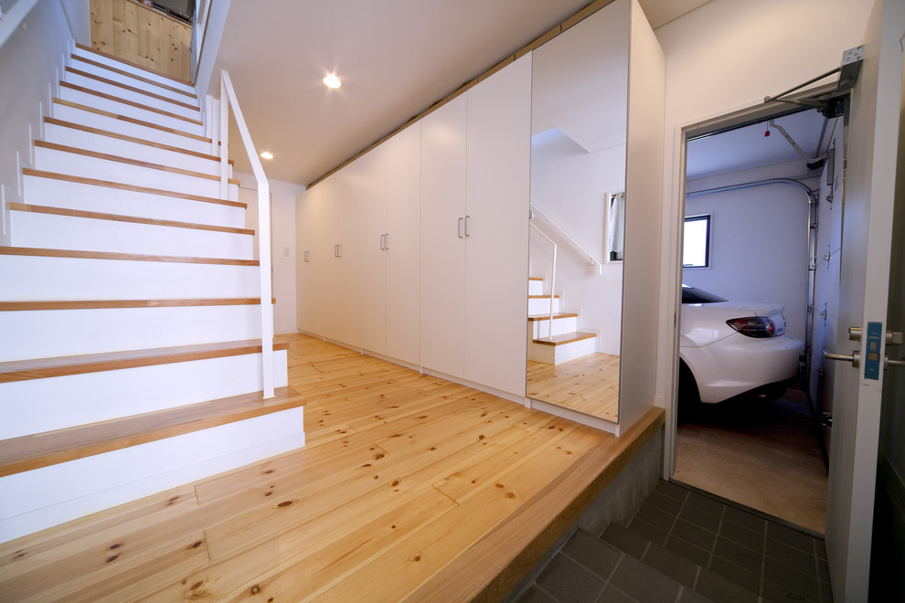 This is an example of a small modern entry hall in Other with white walls, plywood floors, a single front door, a black front door and beige floor.