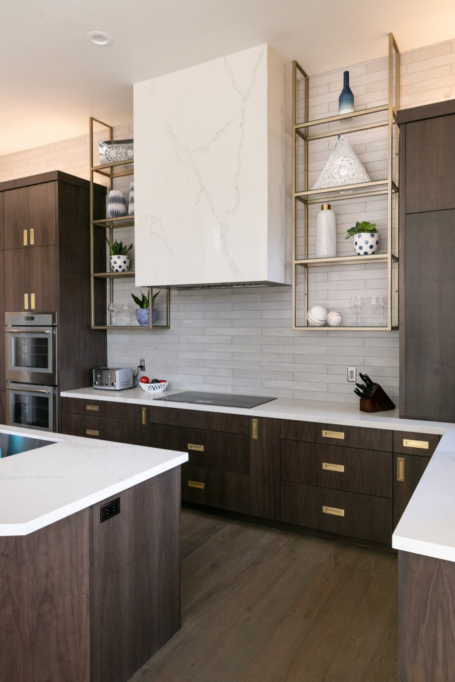 Contemporary l-shaped kitchen in Salt Lake City with an undermount sink, flat-panel cabinets, dark wood cabinets, grey splashback, stainless steel appliances, medium hardwood floors, with island, brown floor and white benchtop.