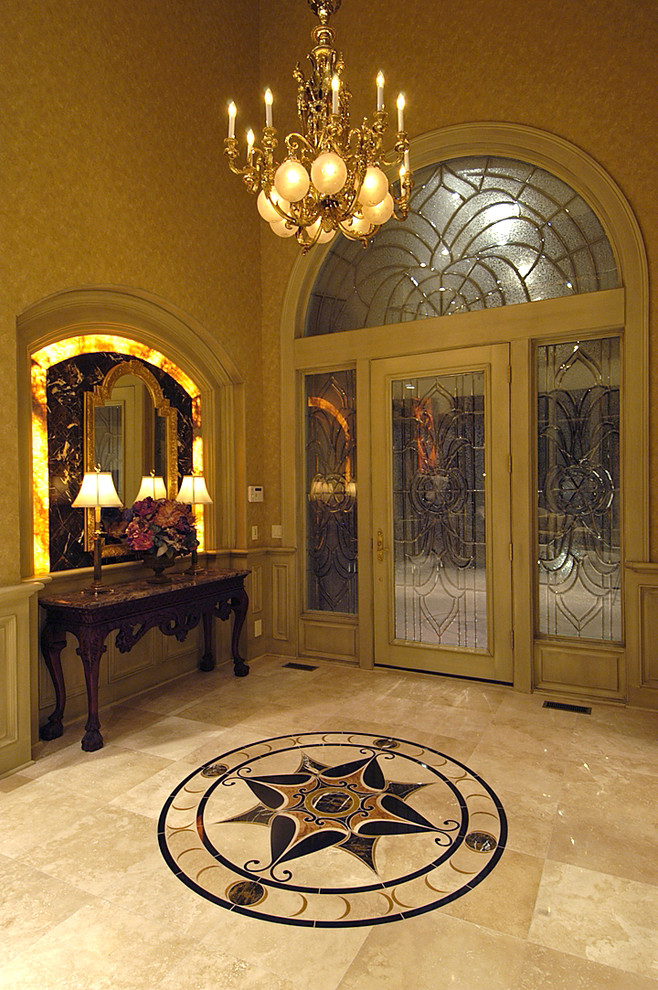 This is an example of an expansive traditional foyer in Omaha with beige walls, travertine floors, a single front door and a glass front door.