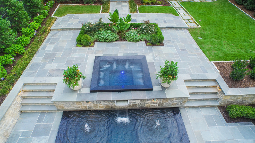 Large traditional backyard rectangular infinity pool in Atlanta with a hot tub and natural stone pavers.