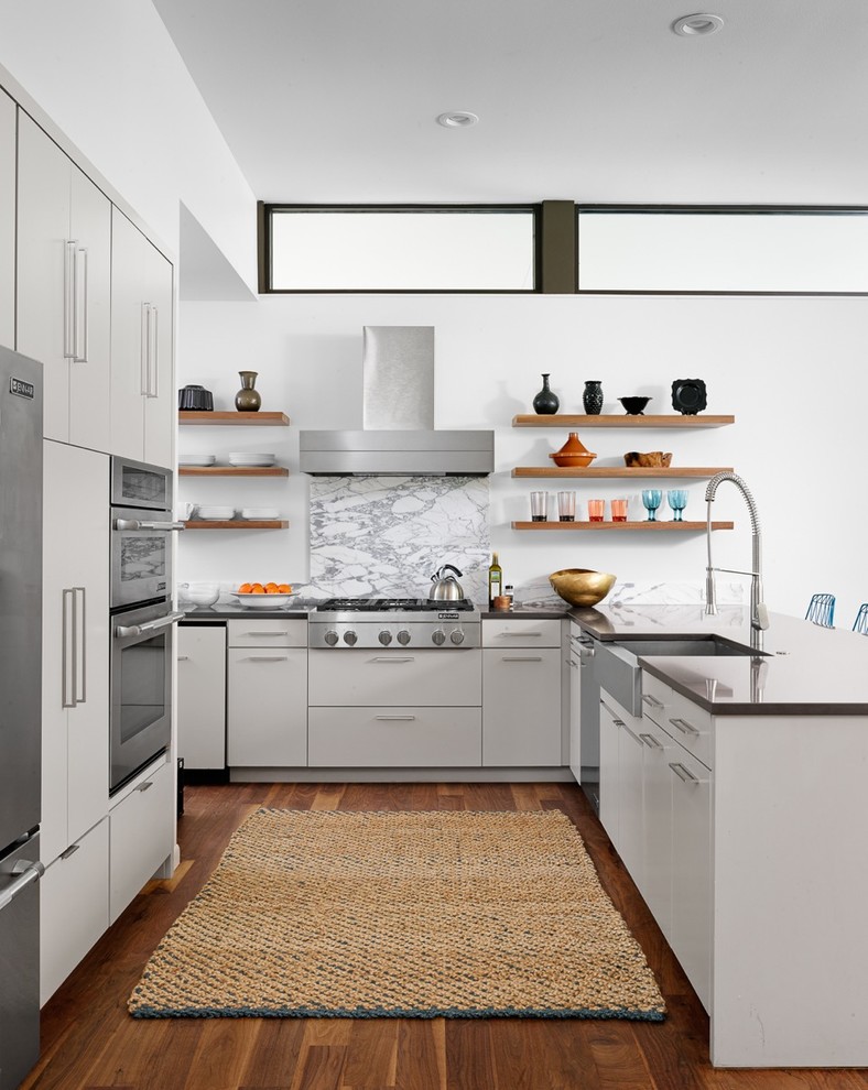 Inspiration for a midcentury u-shaped eat-in kitchen in Austin with a farmhouse sink, flat-panel cabinets, grey cabinets, quartzite benchtops, stone slab splashback, stainless steel appliances, medium hardwood floors and a peninsula.