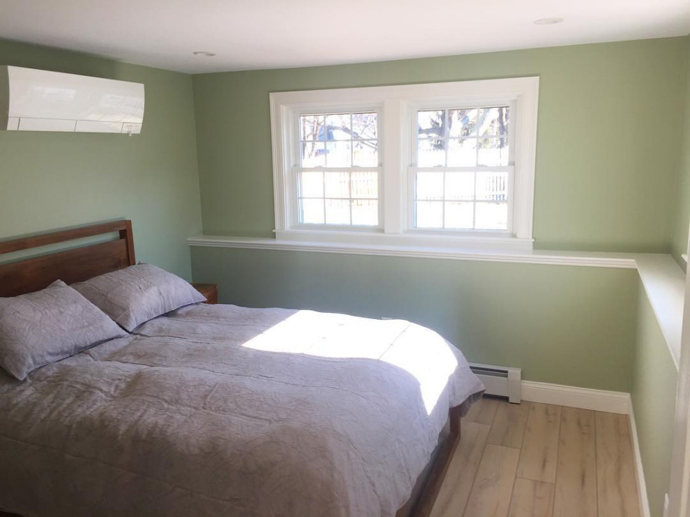 This is an example of a mid-sized transitional guest bedroom in Boston with green walls, light hardwood floors, no fireplace and beige floor.