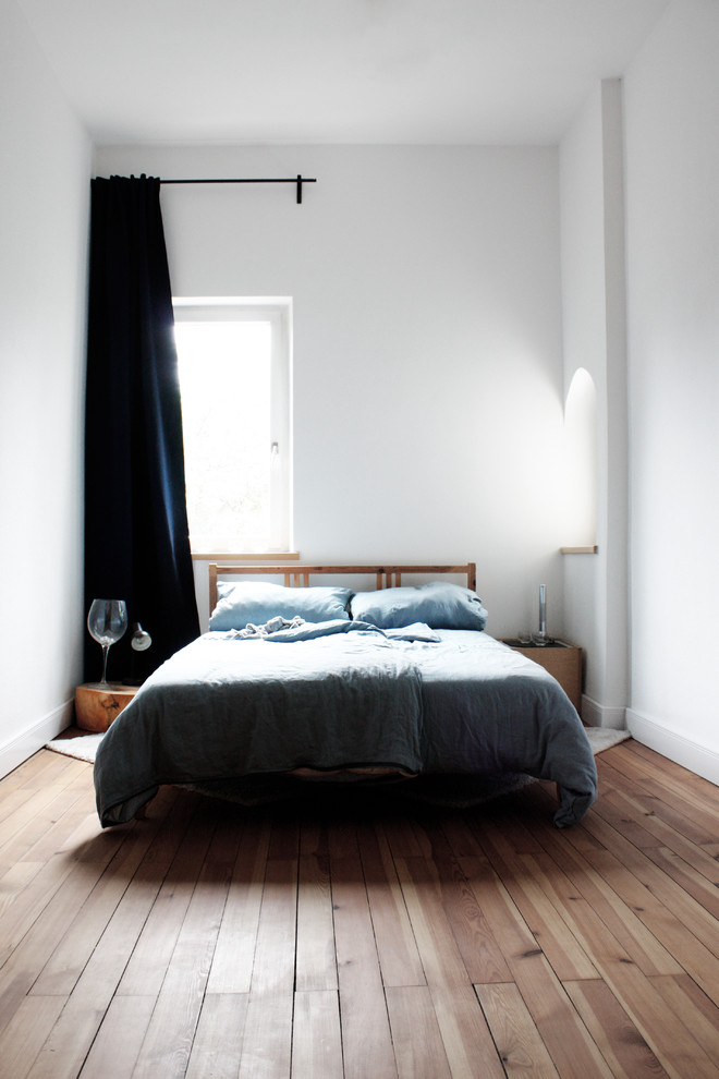 This is an example of a small scandinavian bedroom in Nuremberg with white walls, medium hardwood floors and no fireplace.