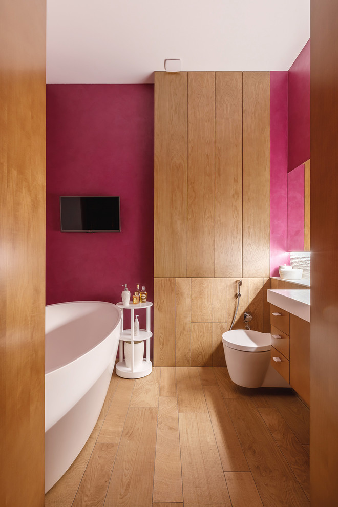 Photo of a contemporary bathroom in Other with flat-panel cabinets, medium wood cabinets, a wall-mount toilet, red walls and brown floor.