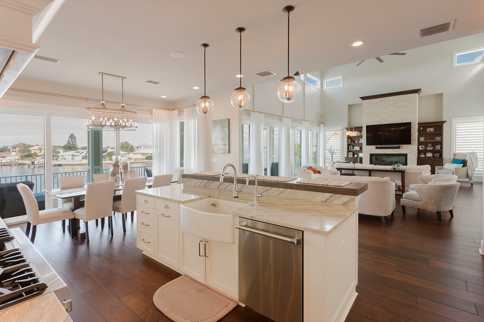 Transitional l-shaped open plan kitchen in Tampa with a farmhouse sink, shaker cabinets, white cabinets, stainless steel appliances, dark hardwood floors, with island, brown floor and beige benchtop.