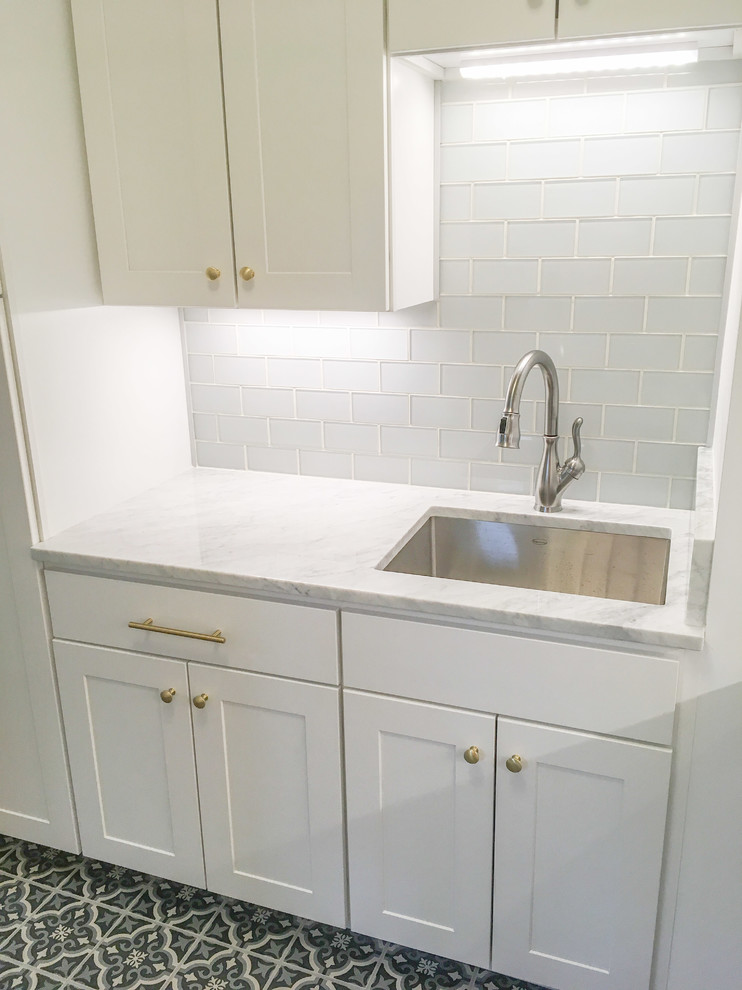 Photo of a small traditional dedicated laundry room in Raleigh with an undermount sink, flat-panel cabinets, white cabinets, marble benchtops, white walls, porcelain floors and a side-by-side washer and dryer.