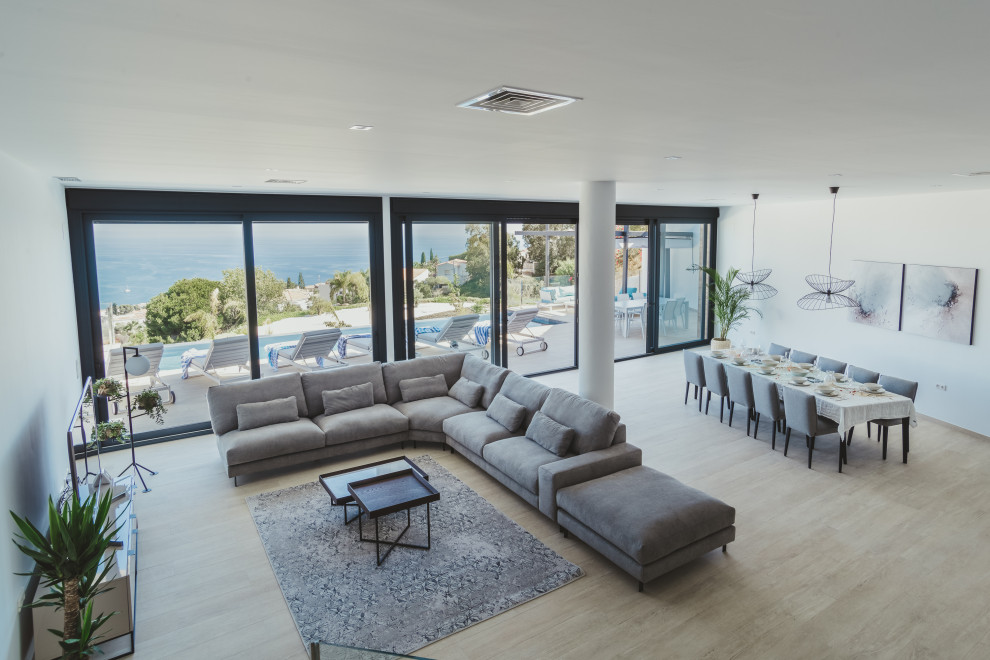 This is an example of a large contemporary open concept living room in Other with white walls, ceramic floors, a freestanding tv and beige floor.