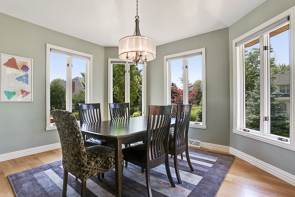 Example of a light wood floor and brown floor dining room design with green walls