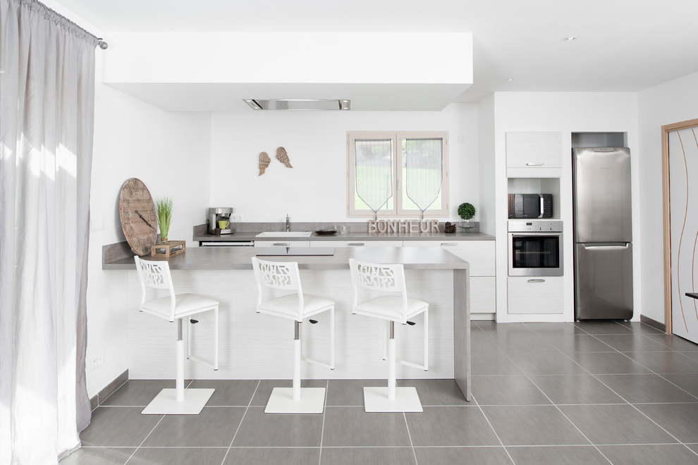 Inspiration for a mid-sized contemporary galley eat-in kitchen in Lyon with a drop-in sink, flat-panel cabinets, white cabinets, stainless steel appliances, ceramic floors, with island and grey floor.