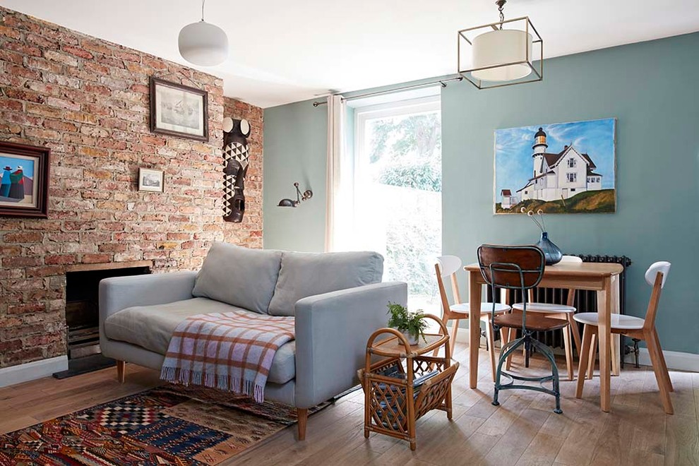 Inspiration for a small arts and crafts living room in London with blue walls, light hardwood floors, a standard fireplace, a brick fireplace surround and brown floor.