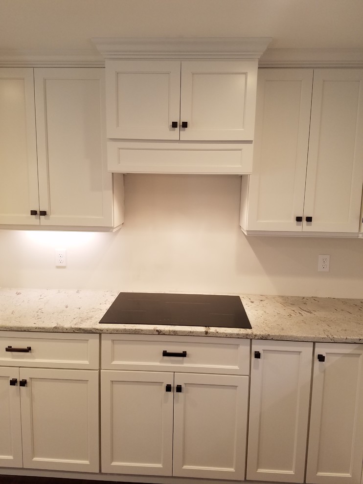 Eat-in kitchen - mid-sized transitional l-shaped dark wood floor and brown floor eat-in kitchen idea with a farmhouse sink, shaker cabinets, white cabinets, granite countertops, white backsplash, subway tile backsplash, stainless steel appliances and an island