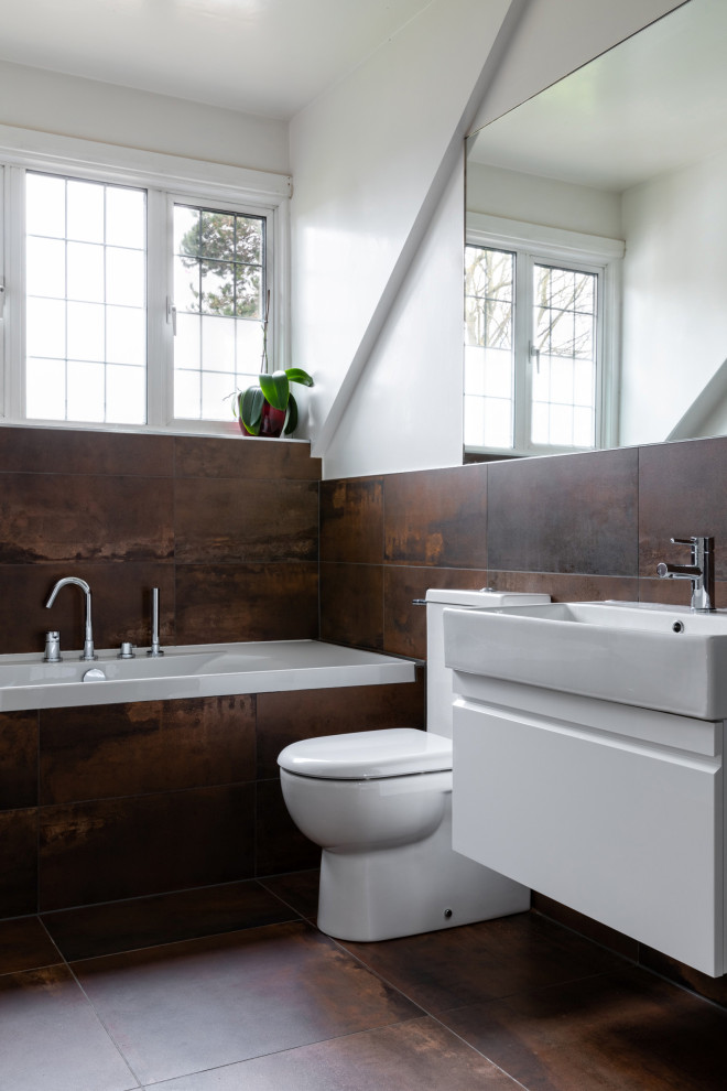 Photo of a mid-sized contemporary kids bathroom in London with white cabinets, a drop-in tub, a curbless shower, a wall-mount toilet, brown tile, white walls, a wall-mount sink, brown floor, a hinged shower door, a niche, a single vanity and a floating vanity.