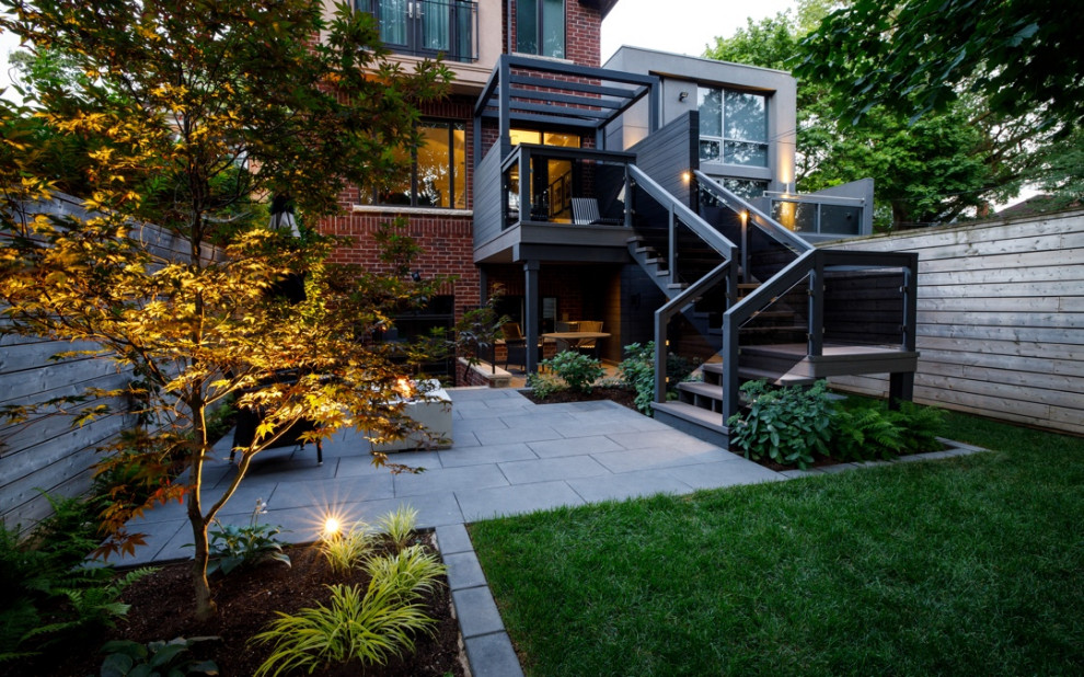 Design ideas for a modern backyard garden in Toronto with brick pavers and a wood fence.