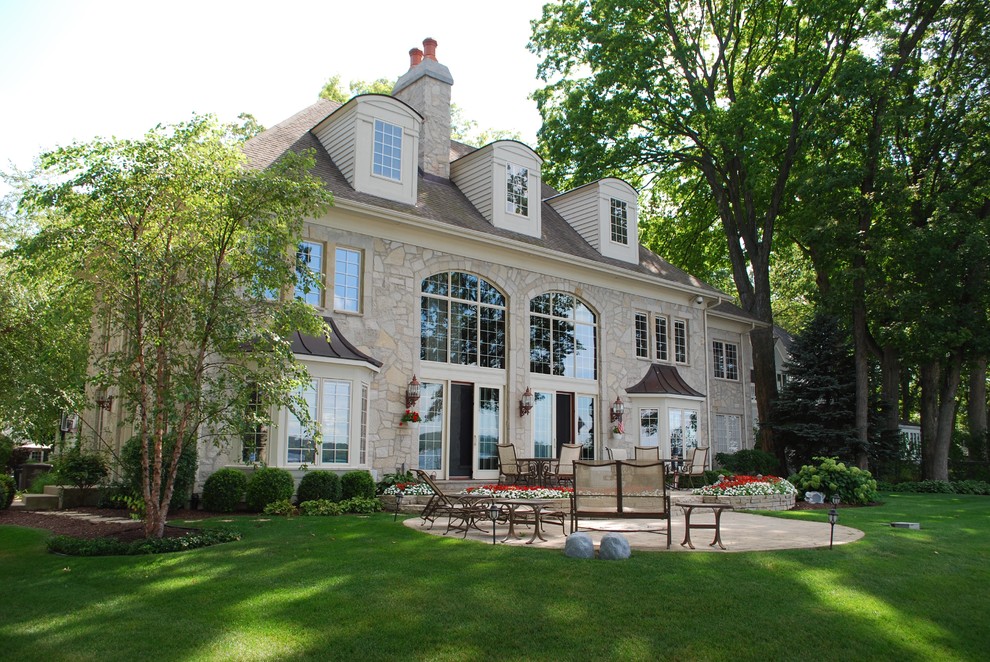 Large traditional three-storey beige house exterior in Chicago with stone veneer and a shingle roof.