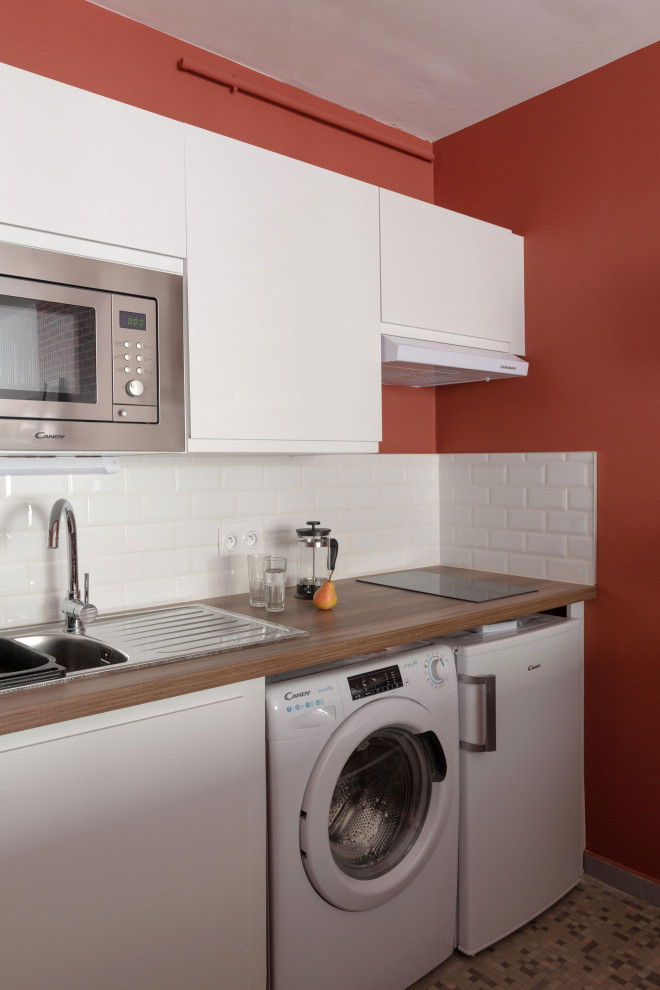 Cette image montre une cuisine américaine linéaire urbaine en bois brun de taille moyenne avec un placard à porte affleurante, un plan de travail en bois, îlot et un plan de travail beige.
