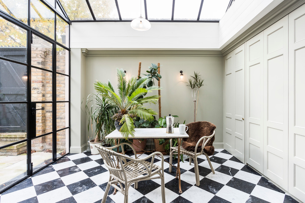 Photo of a transitional sunroom in London with marble floors and a glass ceiling.