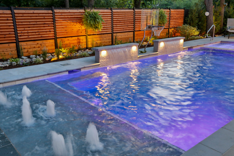 This is an example of a mid-sized traditional backyard rectangular lap pool in Chicago with with privacy feature and natural stone pavers.
