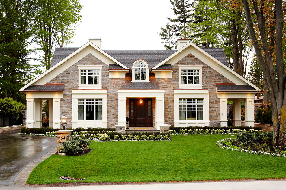Photo of a traditional two-storey exterior in Toronto with stone veneer and a gable roof.