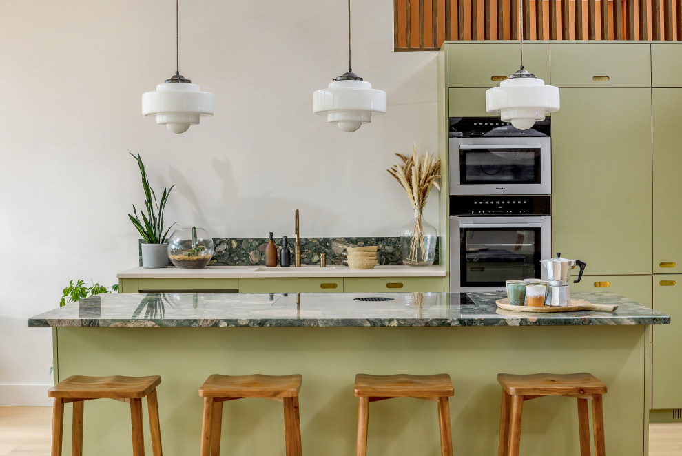 Inspiration for a large midcentury l-shaped open plan kitchen in London with a single-bowl sink, flat-panel cabinets, green cabinets, marble benchtops, green splashback, marble splashback, stainless steel appliances, light hardwood floors, with island, green benchtop and exposed beam.