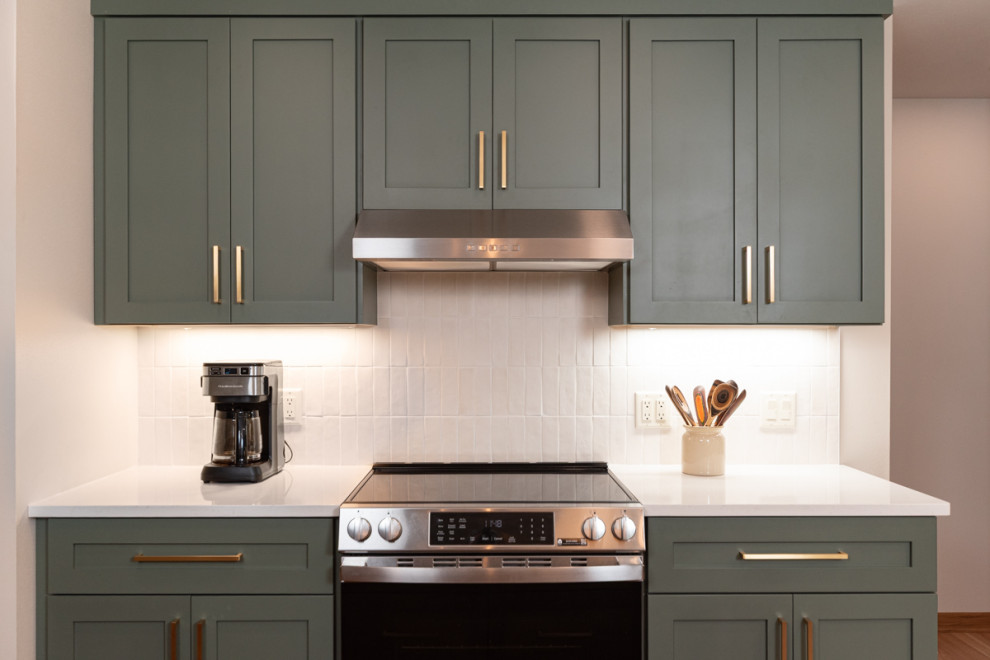 Transitional light wood floor kitchen photo with shaker cabinets, green cabinets, quartz countertops, white backsplash, ceramic backsplash and an island