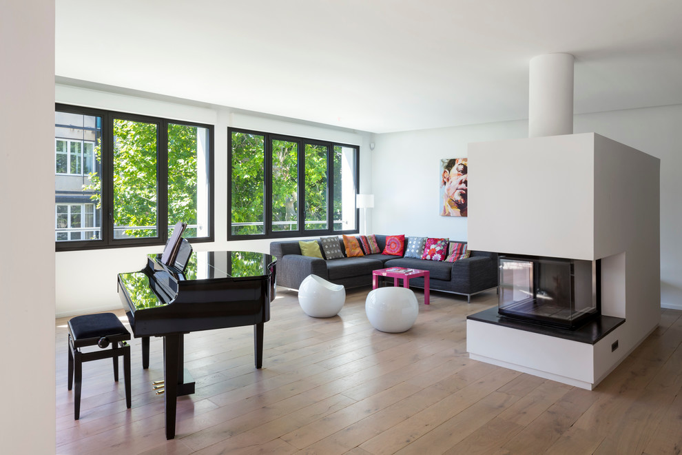 Photo of a large contemporary open concept living room in Marseille with a music area, white walls, medium hardwood floors, a two-sided fireplace, a plaster fireplace surround and no tv.